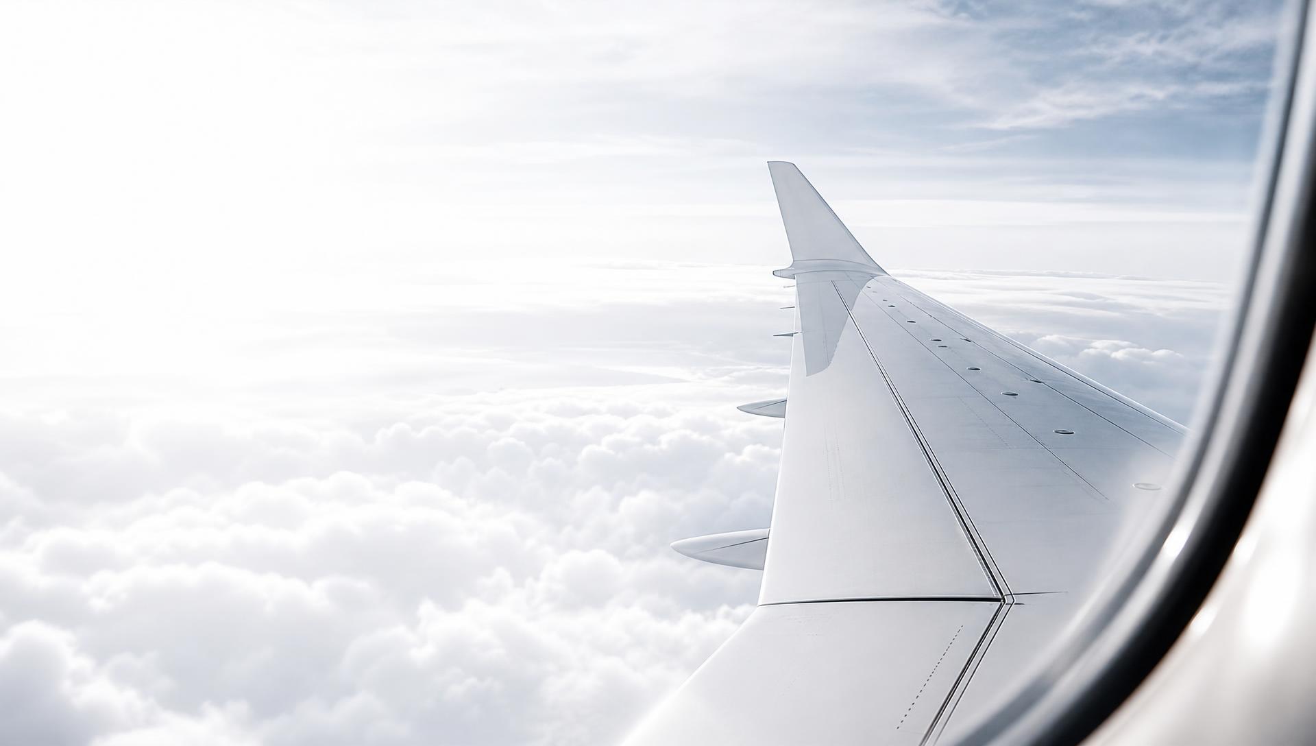 Vue hublot d'un avion blanc en plein vol au-dessus des nuages